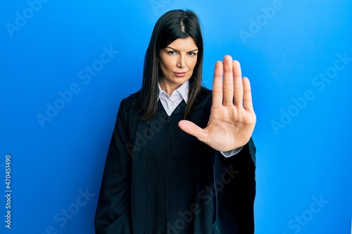 Young hispanic woman wearing judge uniform doing stop sing with palm of the hand. warning expression with negative and serious gesture on the face. photo