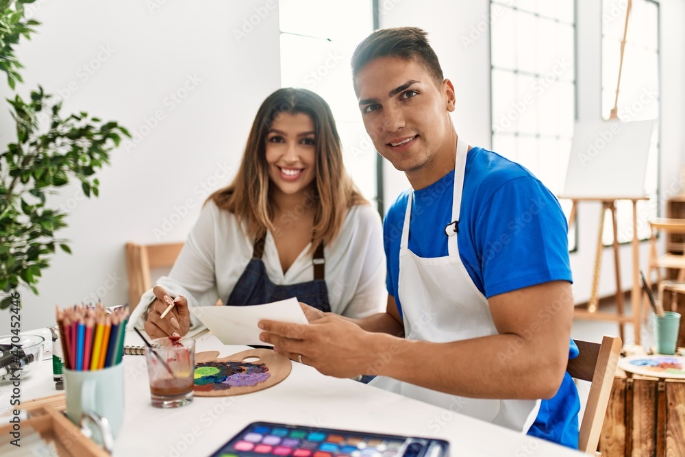 Obraz premium Two students smiling happy painting sitting on the table at art school.