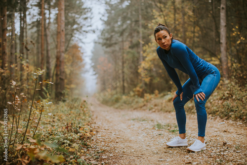 Young woman take a break during outdoor exercise on the forest trail at autumn