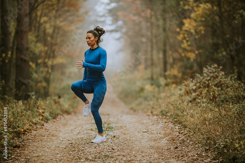 Young woman running having exercise on forest trail at autumn