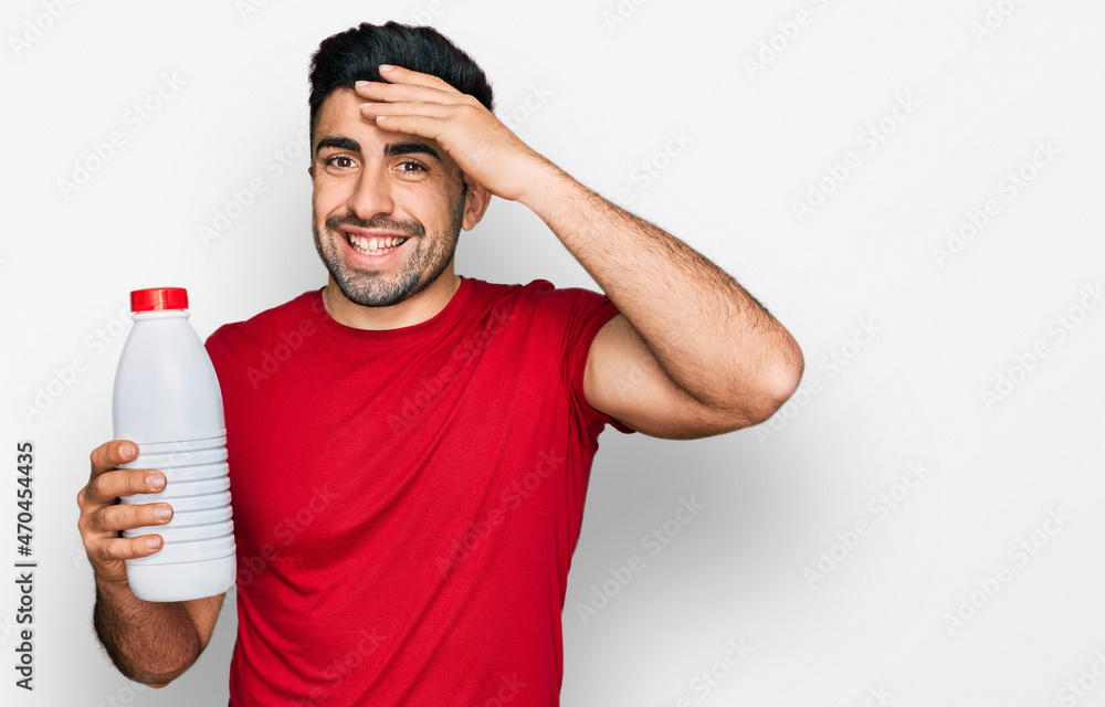 Hispanic man with beard holding liter bottle of milk stressed and frustrated with hand on head, surprised and angry face Hispanic man with beard holding liter bottle of milk stressed and frustrated with hand on head, surprised and angry face