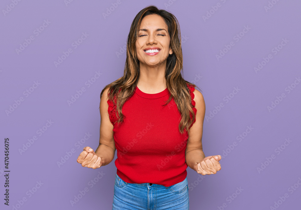 Young hispanic woman wearing casual clothes very happy and excited doing winner gesture with arms raised, smiling and screaming for success. celebration concept. Young hispanic woman wearing casual clothes very happy and excited doing winner gesture with arms raised, smiling and screaming for success. celebration concept.