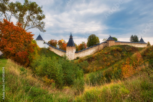 Powerful defensive walls, temples, and beautiful churches in the Dormition Pskovo Pechersky Monastery in the city of Pechery, Pskov Region, Russia during the golden autumn day