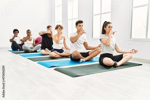 Group of young people concentrate training yoga nadi shodhana breath at sport center.