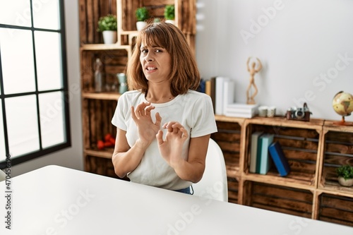 Εκτύπωση καμβά Young caucasian girl wearing casual clothes sitting on the table at home disgusted expression, displeased and fearful doing disgust face because aversion reaction