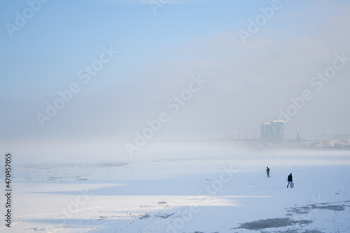 Fishermen on the ice fish in the fog.