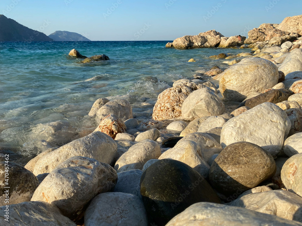 Large beautiful natural round stones and pebbles washed by water on the seashore or ocean against the backdrop of mountains