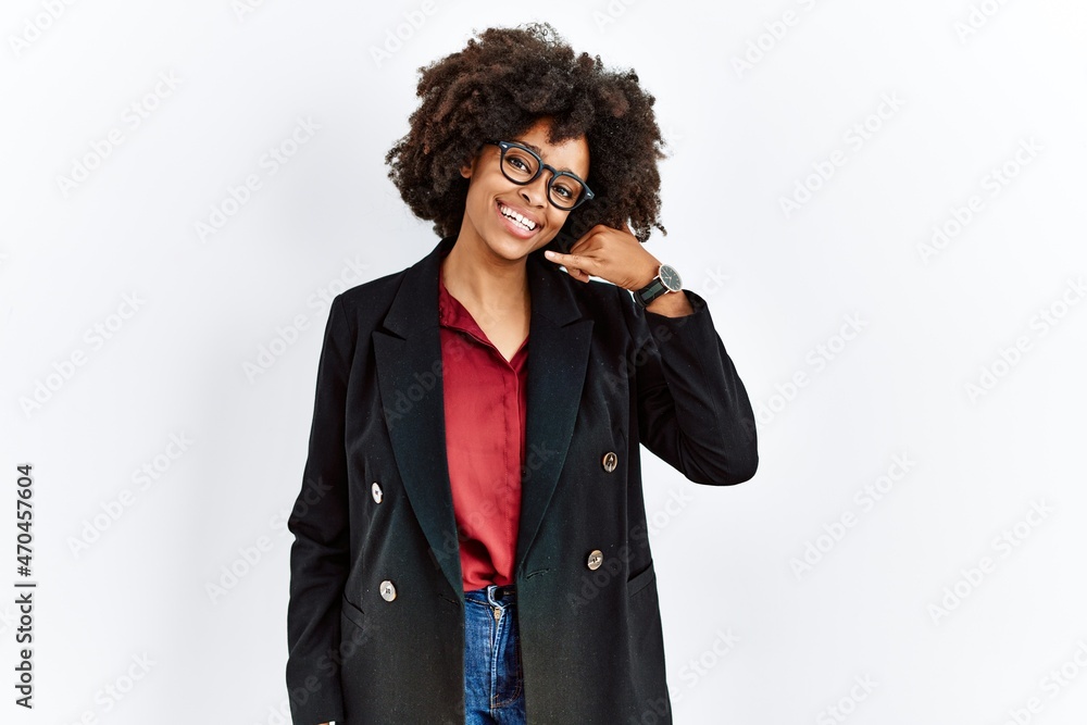 African american woman with afro hair wearing business jacket and glasses smiling doing phone gesture with hand and fingers like talking on the telephone. communicating concepts. African american woman with afro hair wearing business jacket and glasses smiling doing phone gesture with hand and fingers like talking on the telephone. communicating concepts.
