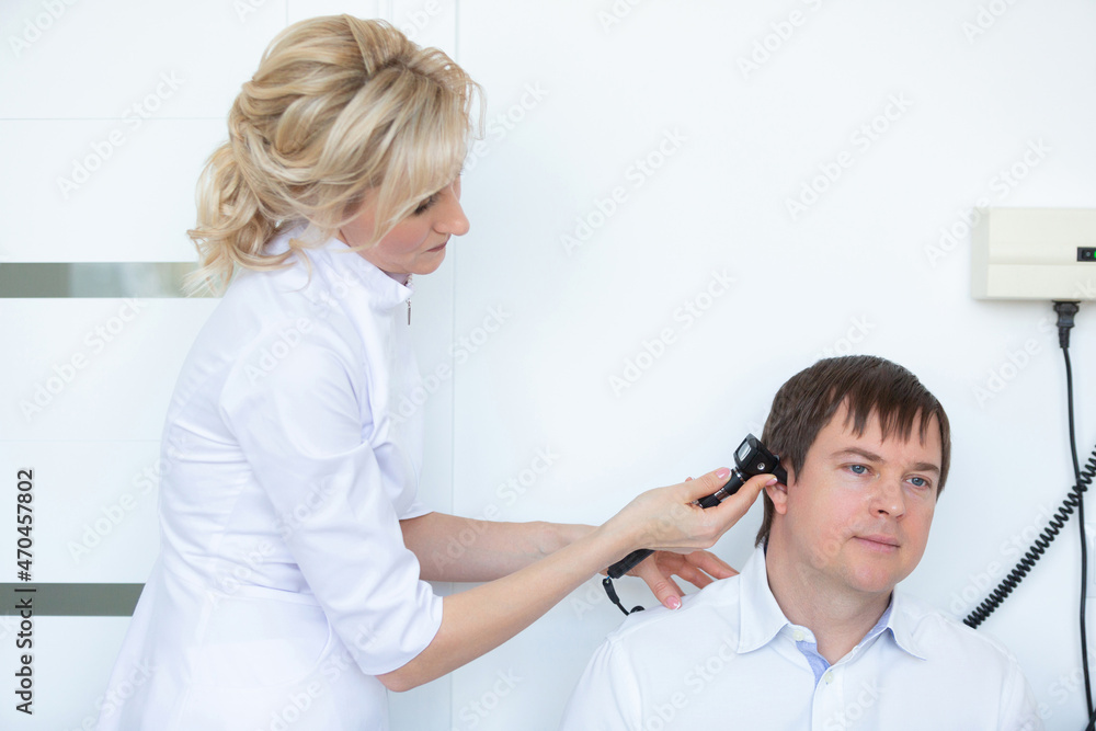 Obraz premium An otorhinolaryngologist examines the external auditory canal of a male patient with an otoscope in the hospital