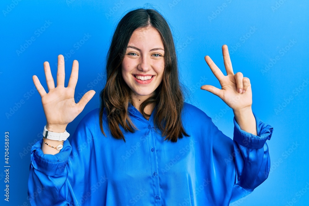 Young brunette woman wearing casual blue shirt showing and pointing up with fingers number eight while smiling confident and happy. Young brunette woman wearing casual blue shirt showing and pointing up with fingers number eight while smiling confident and happy.