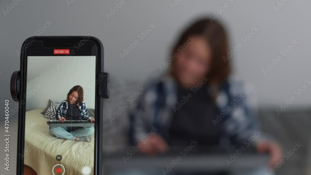 Preteen girl at home playing the electronic piano recording a video for her followers recording a blog. View of smartphone screen recording a girl learning to play a sintezator online as a hobby. Preteen girl at home playing the electronic piano recording a video for her followers recording a blog. View of smartphone screen recording a girl learning to play a sintezator online as a hobby.