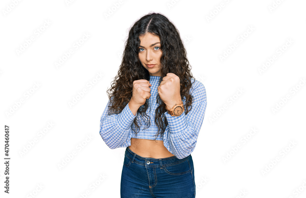 Young hispanic girl wearing casual clothes ready to fight with fist defense gesture, angry and upset face, afraid of problem Young hispanic girl wearing casual clothes ready to fight with fist defense gesture, angry and upset face, afraid of problem