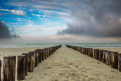 Sandy beach at Burgh-Haamstede in the Dutch province of Zeeland with a double row of posts of beach in the sea intended as functional coastal protection 