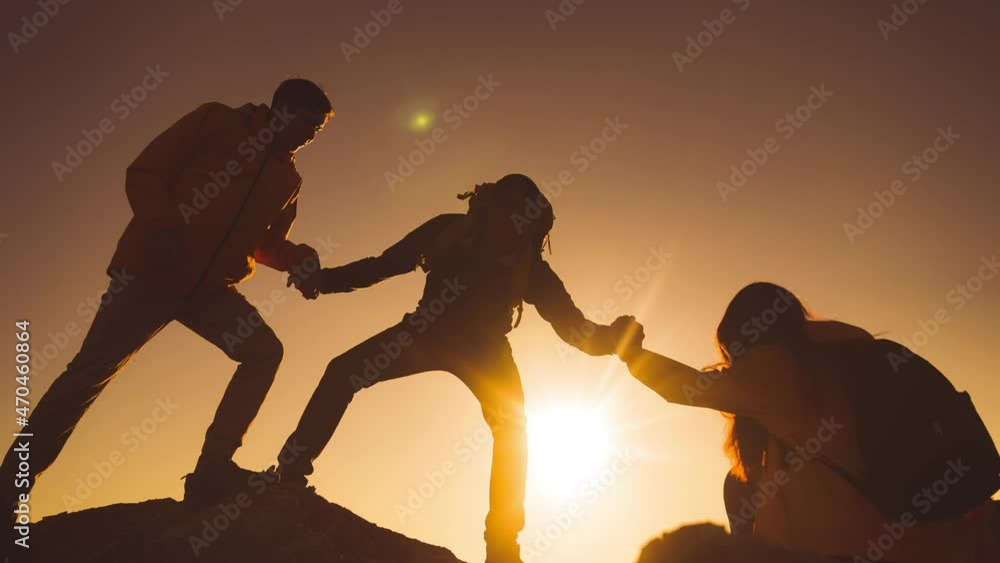 help team concept. team silhouette of climber stretching a helping hand to a friend. business teamwork success concept. silhouette business travel three sunlight tourists pull a helping hand
