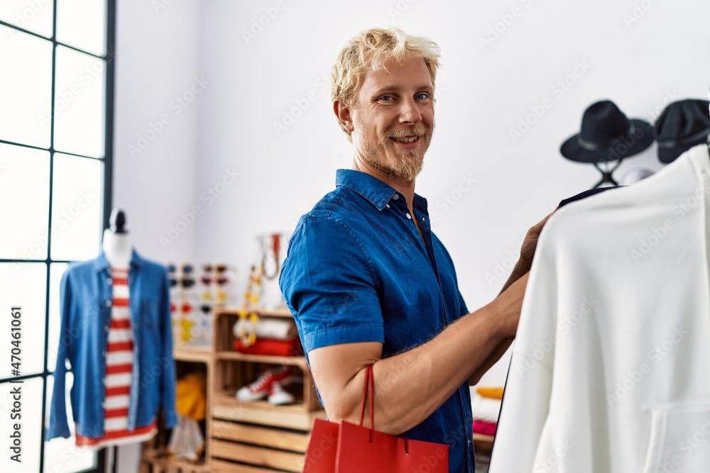 Young caucasian man smiling confident shopping at clothing store