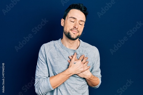 Young hispanic man wearing casual clothes smiling with hands on chest with closed eyes and grateful gesture on face. health concept. © Krakenimages.com