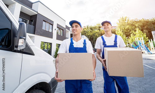 Two removal company workers are loading boxes and furniture into a minibus. © romaset