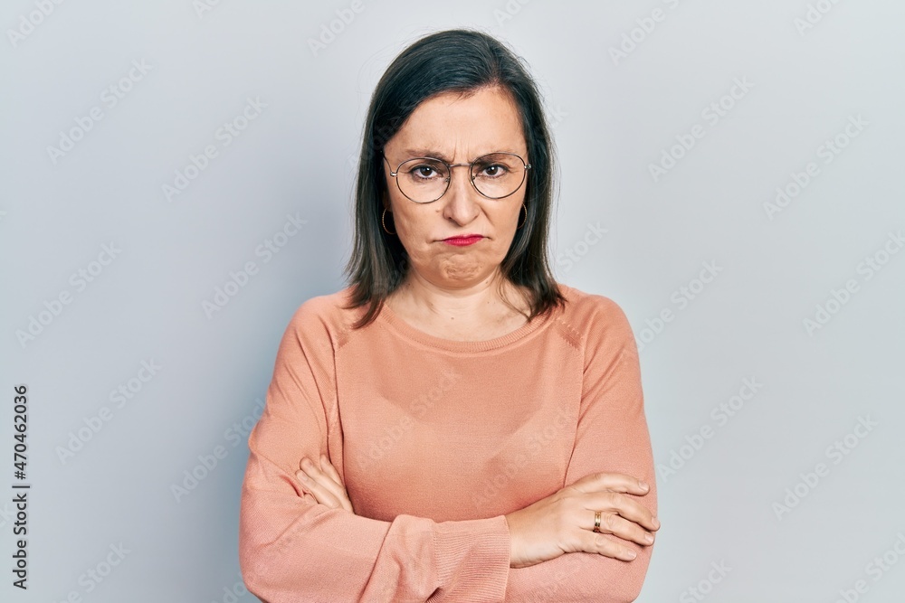 Middle age hispanic woman wearing casual clothes and glasses skeptic and nervous, disapproving expression on face with crossed arms. negative person. Middle age hispanic woman wearing casual clothes and glasses skeptic and nervous, disapproving expression on face with crossed arms. negative person.