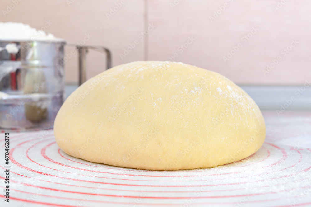 Raw yeast dough on a special silicone baking mat for rolling dough on the kitchen table. Preparation of dough for pizza, pie, baking and other bakery products. The concept of home baking. Raw yeast dough on a special silicone baking mat for rolling dough on the kitchen table. Preparation of dough for pizza, pie, baking and other bakery products. The concept of home baking.