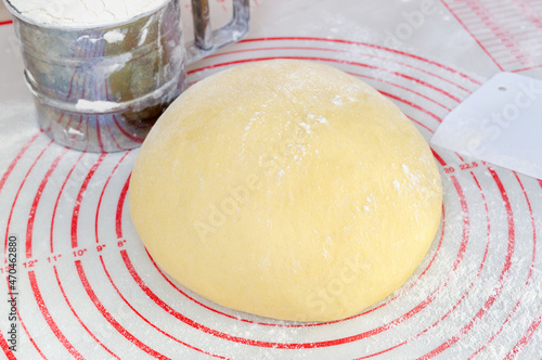 Raw yeast dough on the floured silicone baking mat with markings on the kitchen table.