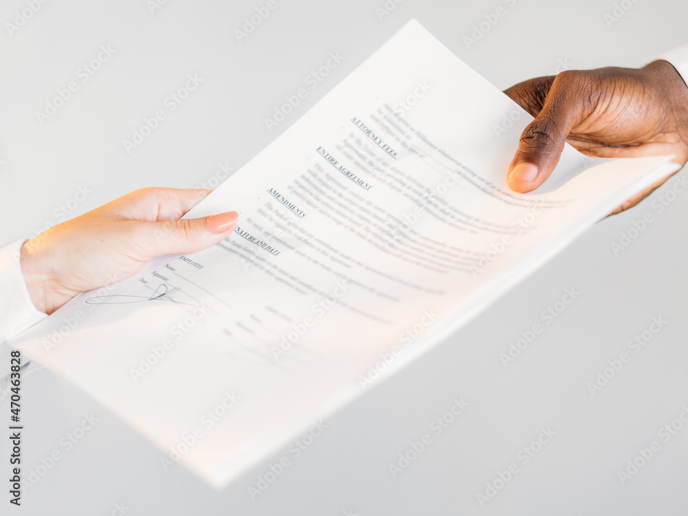 Obraz premium International contract. Global partnership. Multinational agreement. Closeup of diverse business people hands holding agreement paper isolated on neutral.