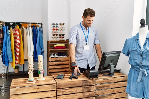 Young hispanic shopkeeper man smiling happy working at clothing store.
