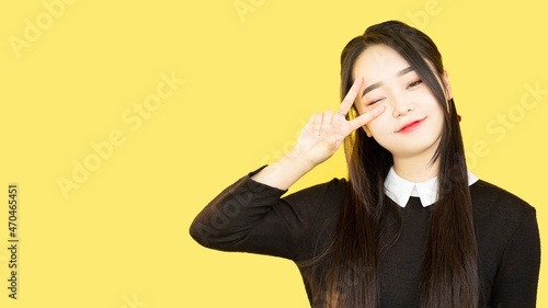 Victory sign. Peace symbol. Optimistic emotion. Promo advertising. Happy winking lovely woman with V two fingers gesture isolated on yellow empty space background.