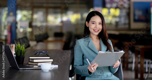 Young asian business woman beautiful charming smiling sitting working in office. Looking at camera.