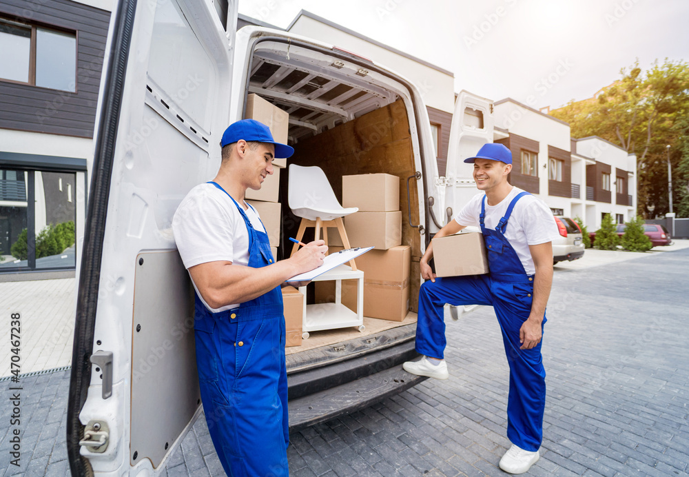 Two removal company workers unloading boxes and furniture from minibus Two removal company workers unloading boxes and furniture from minibus