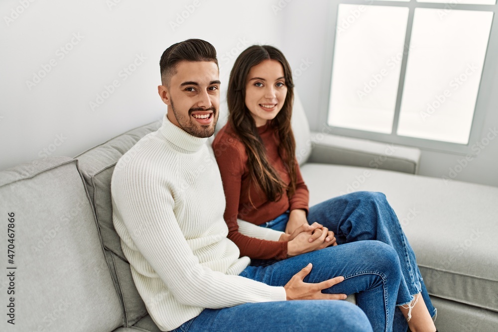 Obraz premium Young hispanic couple hugging and resting on the sofa and at home.