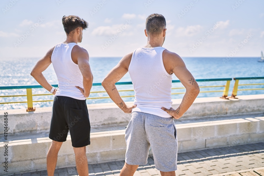 Fototapeta premium Two hispanic men sporty couple on back view looking sea standing at seaside