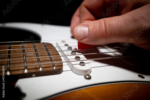 an electric guitar is played with a red pick