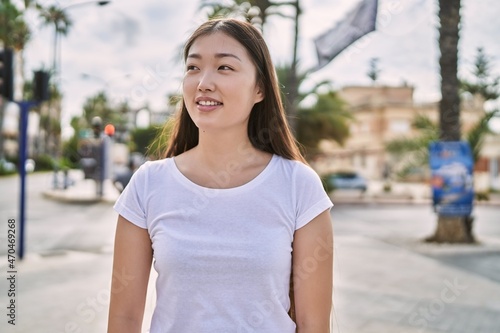 Young chinese girl smiling happy standing at the city.