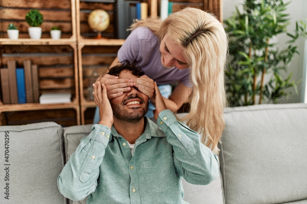 Woman surprising her boyfriend with hands on eyes at home. Woman surprising her boyfriend with hands on eyes at home.