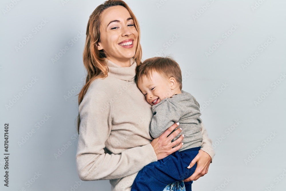 Young caucasian woman holding and hugging her son with love. Family of two bonding together. Mother holding infant toddler Young caucasian woman holding and hugging her son with love. Family of two bonding together. Mother holding infant toddler