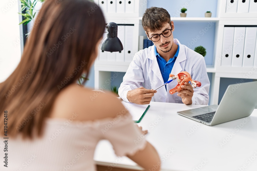 Man and woman wearing doctor uniform having gynecology consultation holding uterus at clinic Man and woman wearing doctor uniform having gynecology consultation holding uterus at clinic
