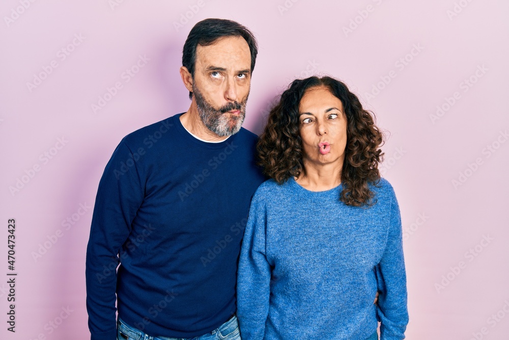 Middle age couple of hispanic woman and man hugging and standing together making fish face with lips, crazy and comical gesture. funny expression. Middle age couple of hispanic woman and man hugging and standing together making fish face with lips, crazy and comical gesture. funny expression.