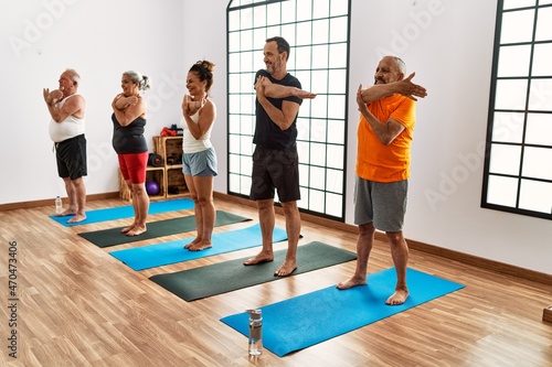 Group of middle age people smiling happy stretching at sport center.