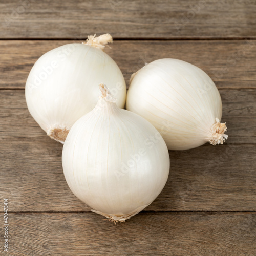 A group of three white onions over wooden table