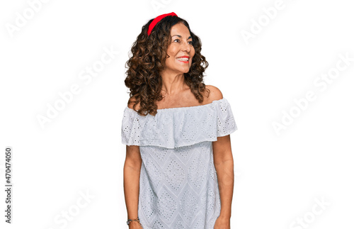 Fotografie Middle age hispanic woman wearing casual clothes looking away to side with smile on face, natural expression