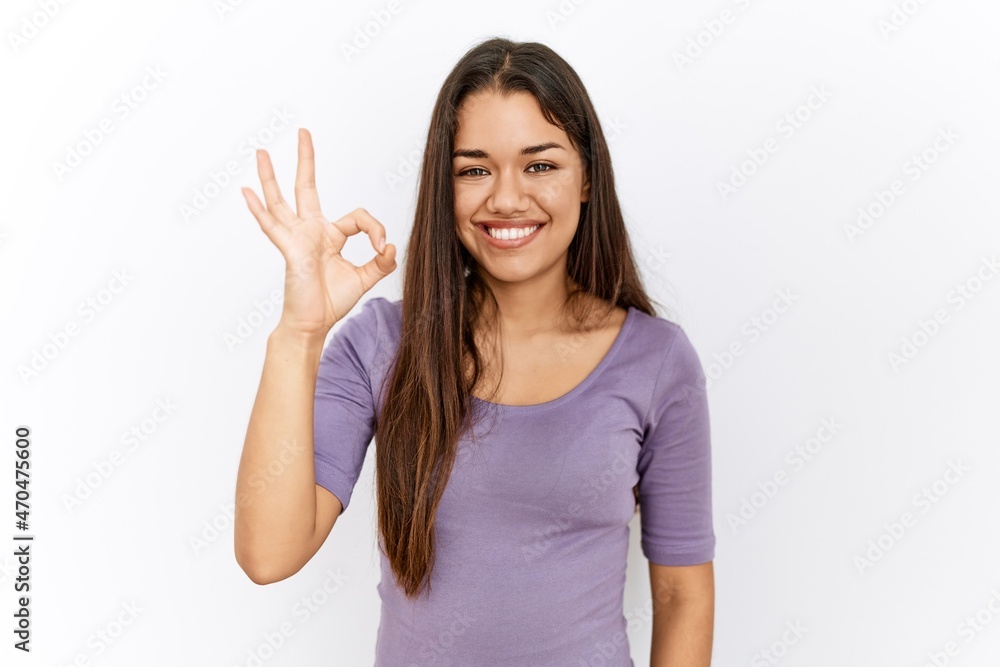 Young brunette woman standing by isolated background smiling positive doing ok sign with hand and fingers. successful expression. Young brunette woman standing by isolated background smiling positive doing ok sign with hand and fingers. successful expression.