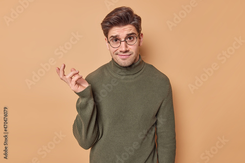 Canvas Print Puzzled confused man with dark hair has doubtful expression makes choice shrugs