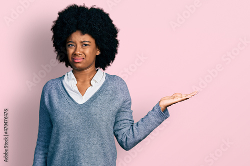 Young african american woman presenting with open palm clueless and confused expression. doubt concept.