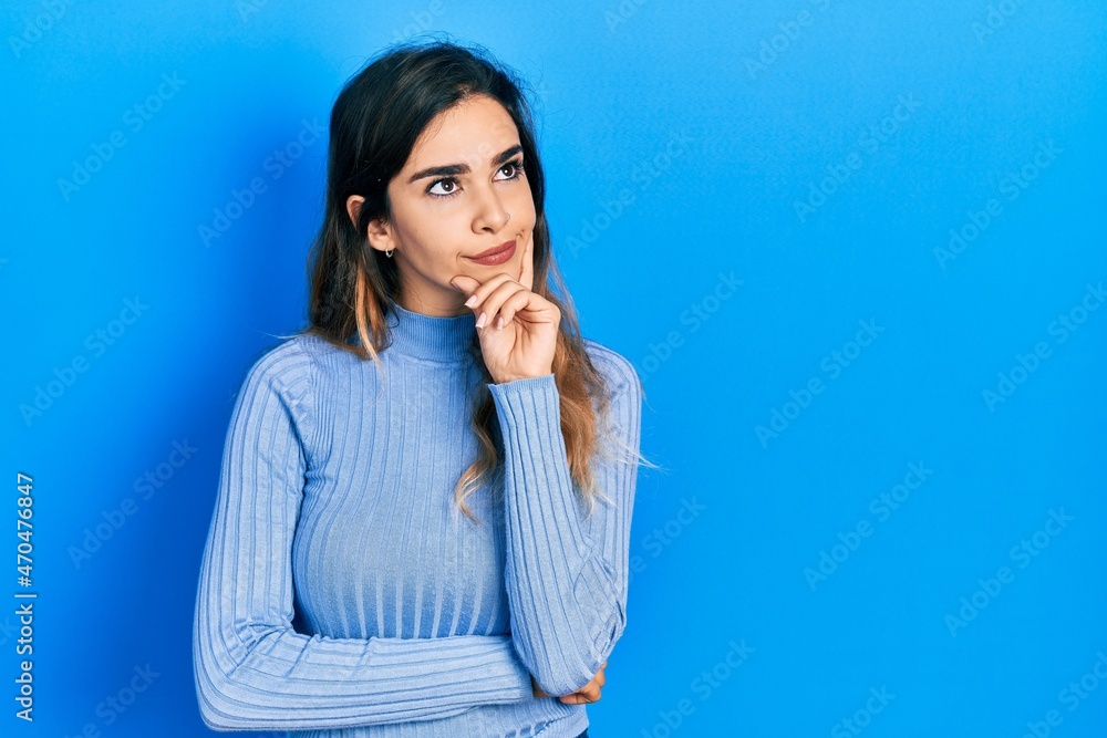 Young hispanic girl wearing casual clothes with hand on chin thinking about question, pensive expression. smiling with thoughtful face. doubt concept. Young hispanic girl wearing casual clothes with hand on chin thinking about question, pensive expression. smiling with thoughtful face. doubt concept.