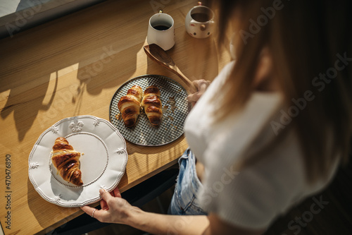 Fresh croissants on a plate. The girl puts croissants on a plate