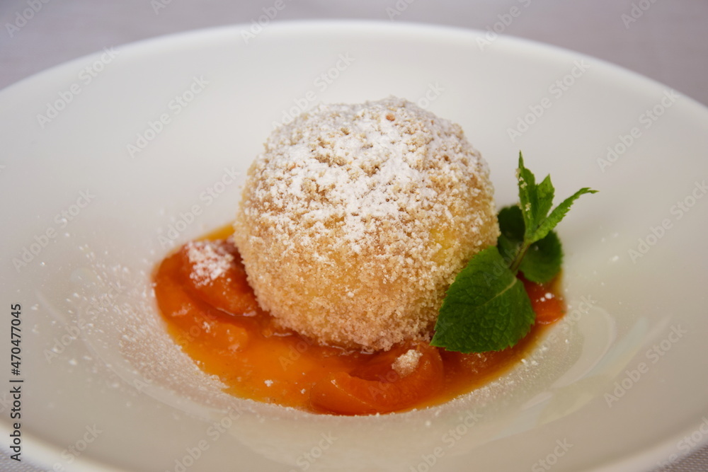 Marillenknödel mit Marillenröster, Süße Knödel mit Staubzucker und Semmelbrösel auf weißen Teller. Traditionelle Nachspeise aus Südtirol und Österreich Marillenknödel mit Marillenröster, Süße Knödel mit Staubzucker und Semmelbrösel auf weißen Teller. Traditionelle Nachspeise aus Südtirol und Österreich