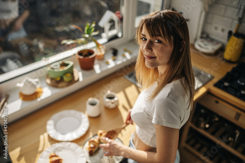 Young attractive girl in the kitchen with croissants in a white T-shirt and jeans