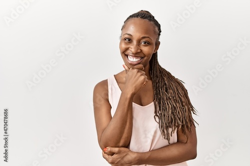 Black woman with braids standing over isolated background looking confident at the camera smiling with crossed arms and hand raised on chin. thinking positive.