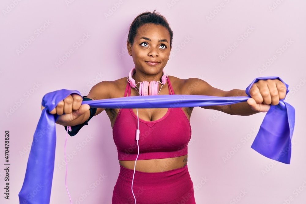 Young african american girl training arm resistance with elastic arm bands smiling looking to the side and staring away thinking. Young african american girl training arm resistance with elastic arm bands smiling looking to the side and staring away thinking.