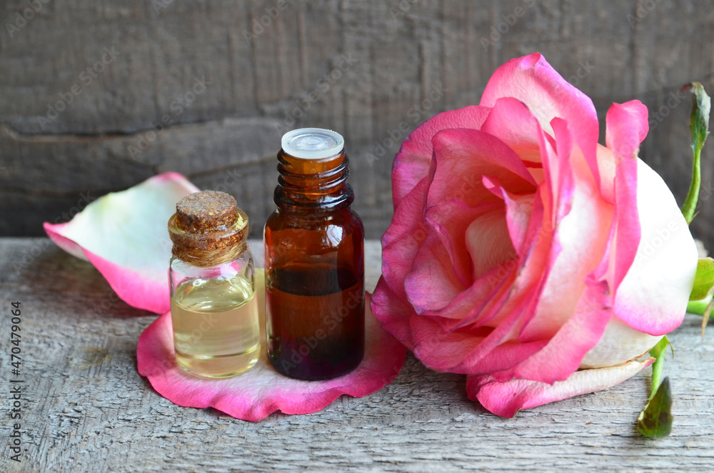 Rose essential oil in a glass bottle on old wooden table.Spa, skin care or aromatherapy concept.Organic cosmetics.Selective focus Rose essential oil in a glass bottle on old wooden table.Spa, skin care or aromatherapy concept.Organic cosmetics.Selective focus